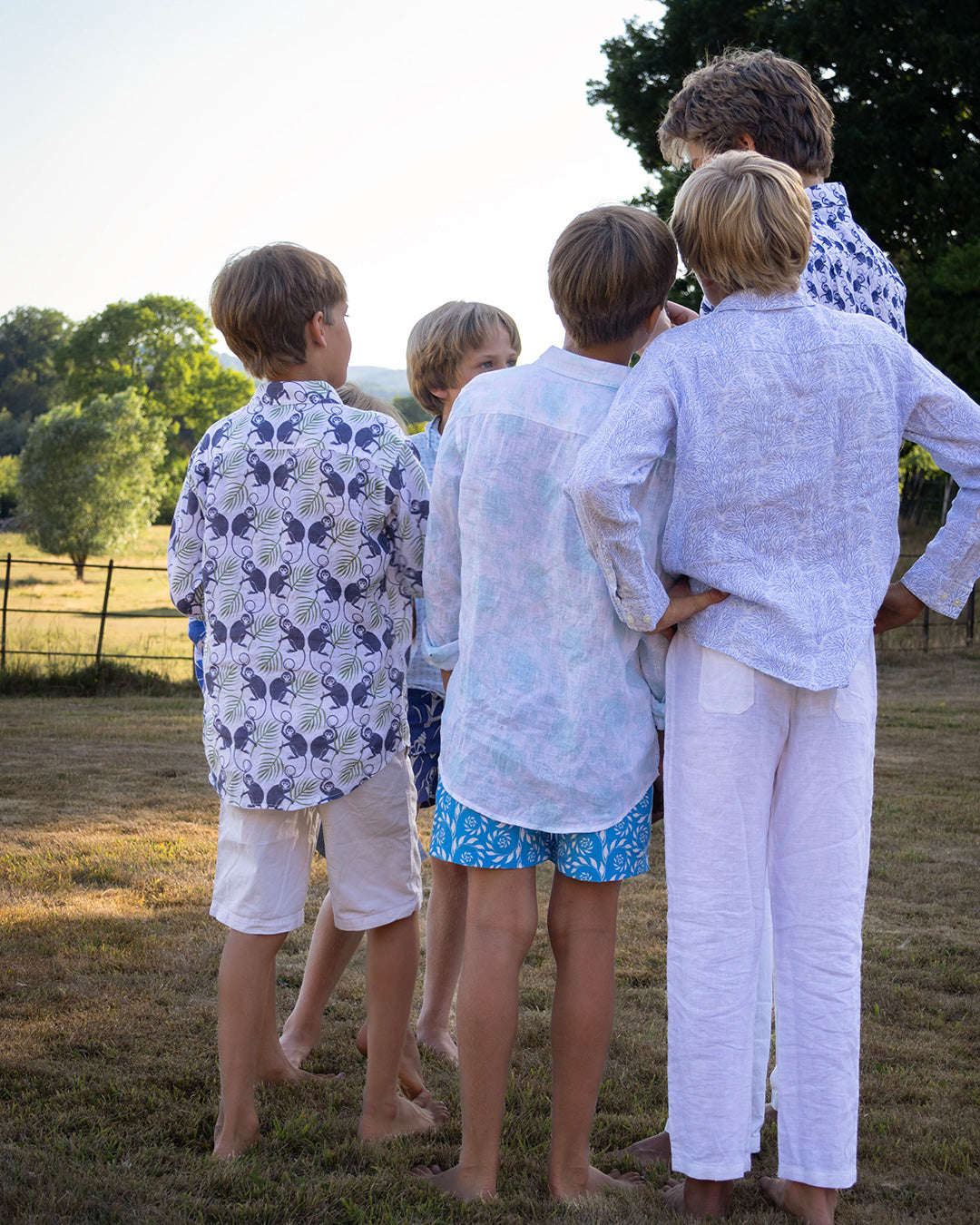 Unisex kids linen shirts in monkey and palms print, plum navy and green, styled for summer family holidays