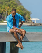Mens bright turquoise linen shirt modeled on Cotton House pier, Mustique island