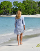 Katie walking along Lagoon Beach wearing Pink House Mustique Coral Stone Blue linen Decima dress.