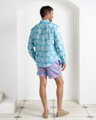 Back view of men’s Agave turquoise linen shirt with coordinating Agave pink and turquoise print swim shorts.