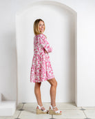 Parrot pink silk crepe Amy dress with tiered skirt and soft gathers, shown in three-quarter profile studio image