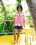 Men's silk Festival Shirt in Banana Tree Pink by Lotty B, styled with navy swim shorts on Mustique villa terrace