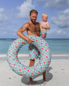 Father and toddler in matching Watermelon print swim shorts with beach ring on a Caribbean beach