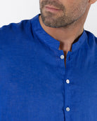 Close up of mens dazzling blue linen shirt with collarless grandad Nehru collar and button front, lightweight summer fabric
