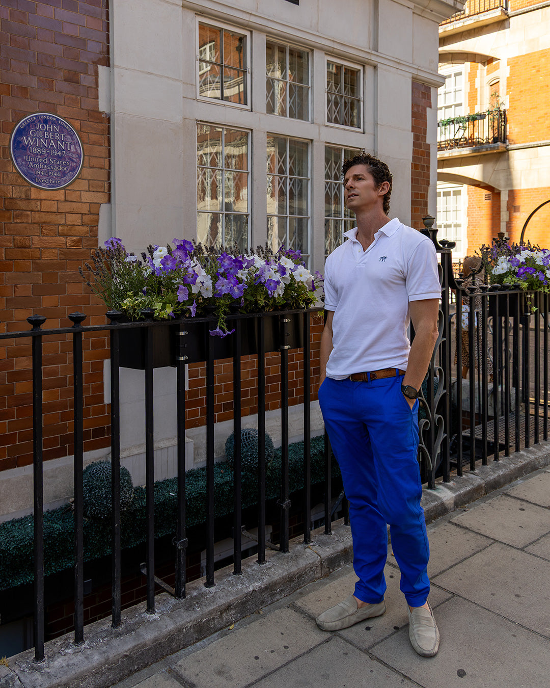 Men's white cotton polo shirt with dazzling blue stretch linen trousers styled for smart summer city wear in London