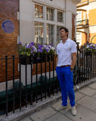 Men's white cotton polo shirt with dazzling blue stretch linen trousers styled for smart summer city wear in London