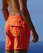Back view of men’s orange swim shorts with pocket detail, premium resort swimwear
