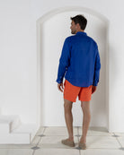 Men’s orange swim shorts with blue linen shirt, back view, luxury resortwear styling