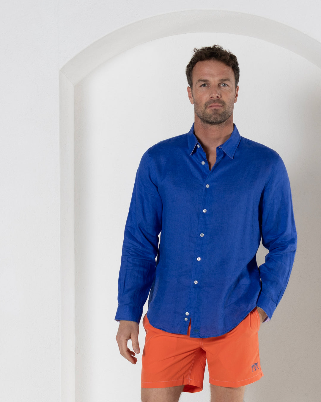 Men’s orange swim shorts styled with blue linen shirt, front view, smart resort wear