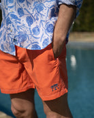 Men’s orange swim shorts with linen shirt, poolside detail, relaxed luxury holiday look