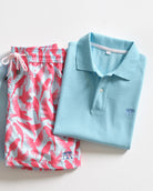 Pink House Mustique pale blue cotton polo shirt styled with pink Parrot print men's swim shorts