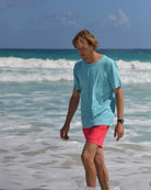 Men's pale blue cotton T-shirt and faded red swim shorts on a Caribbean beach in Mustique