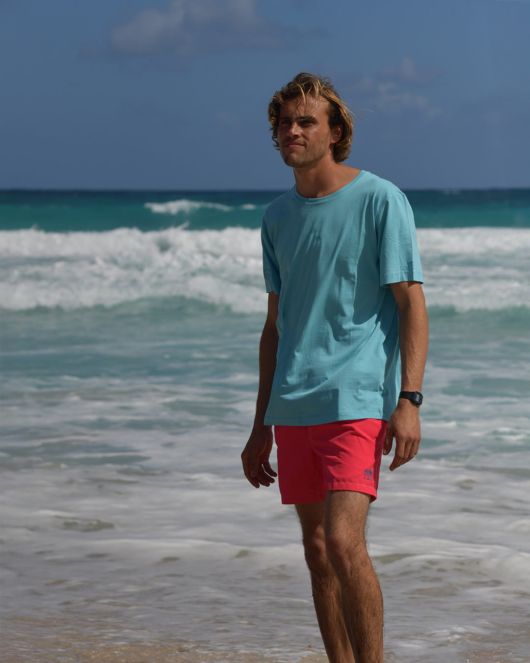 Men's pale blue cotton T-shirt styled with faded red swim shorts on the beach in Mustique