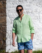 Mens pistachio green linen grandad collar shirt with buttoned cuffs styled with monkey plum swim shorts