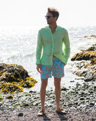 Mens pistachio green linen shirt with grandad Nehru collar styled with green pink monkey print swim shorts on beach