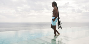 man walking in water with blue swim shorts on