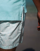 Detail view of men’s Coral Stone Aqua print swim shorts by Pink House Mustique, resort 26 collection.