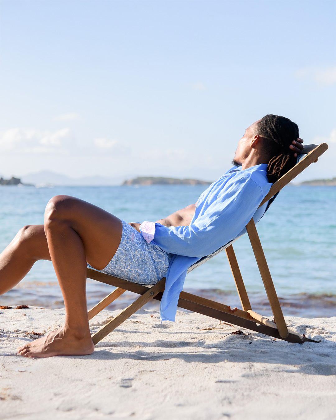 Men’s Coral Stone Blue swim shorts and French blue linen shirt by Pink House Mustique, relaxed Lagoon Beach style.