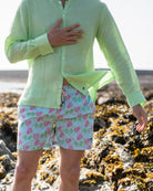Mens pistachio green linen shirt detail showing lightweight fabric and button front with green pink monkey print swim shorts