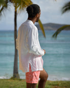 Mens white linen collarless shirt back view on beach with swim shorts, relaxed resort style with Nehru collar