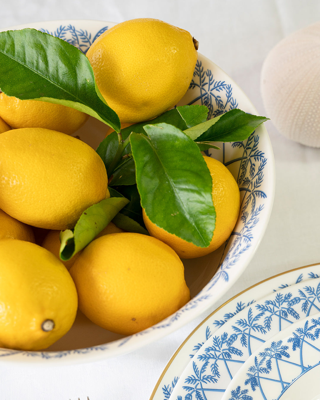 Fine bone china round serving bowl in Palms Azure Blue filled with fresh lemons – handcrafted British porcelain tableware by Lotty B Mustique