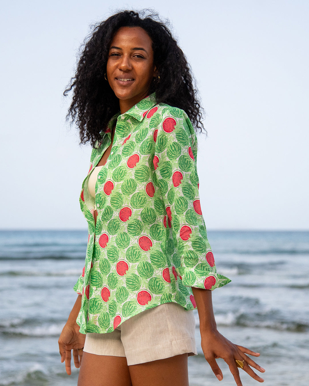 Anastasia women's linen shirt in Watermelon Green print styled with natural shorts by the sea