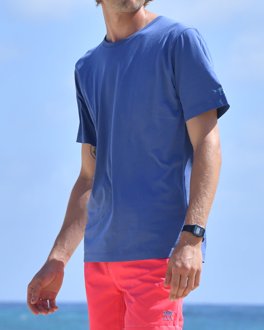 Pink House plain navy T shirt with faded red swim shorts worn on Pasture Bay beach, Mustique Island