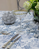 Pink House Toile blue cotton tablecloth styled with glassware and flowers for an elegant dining table