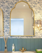 Pink House Toile Wallpaper in Semley Blue in a bathroom with blue panelling and gold-framed mirror