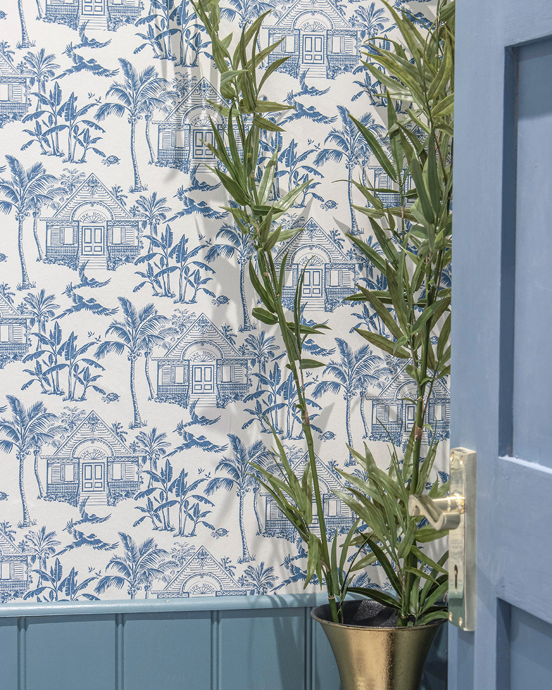 Pink House Toile Wallpaper in Semley Blue styled with blue panelling and tropical greenery