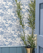 Pink House Toile Wallpaper in Semley Blue styled with blue panelling and tropical greenery