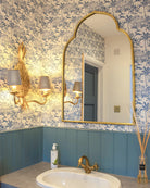 Pink House Toile Wallpaper in Semley Blue in a washroom with blue panelling, brass fittings and gold mirror