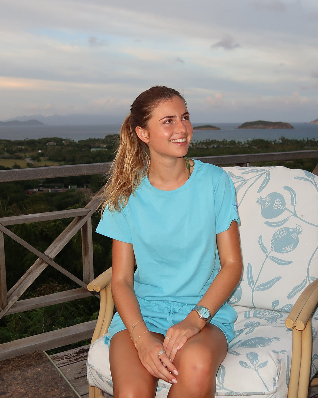 Woman modelling Pink House pale blue pure cotton T-shirt with island view, effortless Mustique beach style