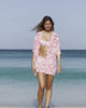 Lottie modeling Parrot pink silk festival shirt, shorts and sustainable bikini on Lagoon Beach, Mustique Island.