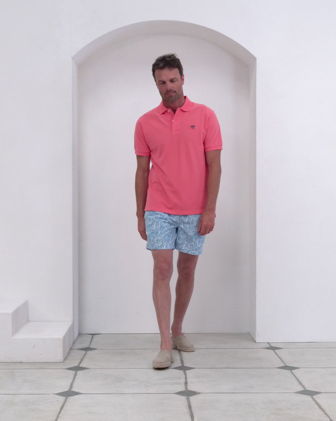 Men’s pink cotton polo and Coral Stone dusk print swim shorts in recycled fabric, Pink House Mustique.