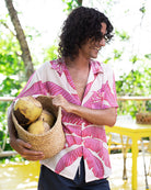 Tropical silk Banana Tree print shirt in pink and white, worn open with navy shorts for relaxed island style