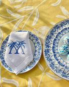 Spring tablescape with Palms Azure Blue fine bone china plates styled on Pomegranate Yellow tablecloth.