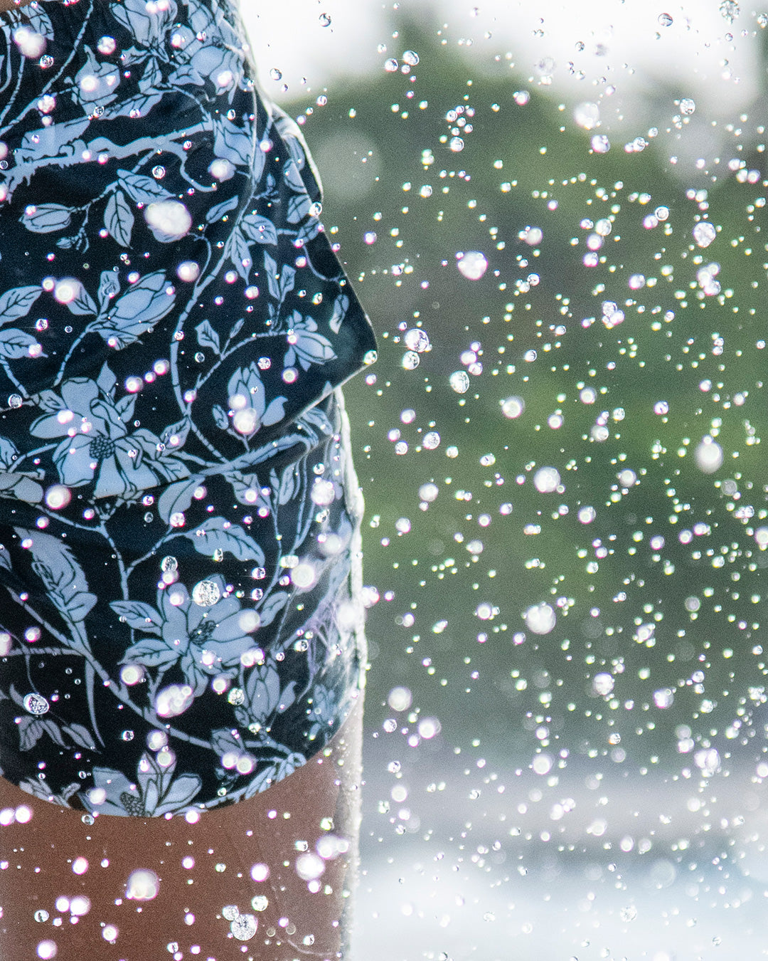 Close-up of Iguana Magnolia spruce swim shorts splashing through surf, Resort 26 Pink House Mustique.