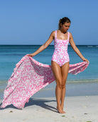Lottie wears Parrot Pink Square Neck Swimsuit with matching silk sarong, photographed on Lagoon Bay, Mustique Island – designed by Lotty B