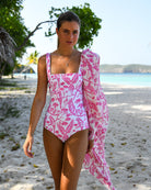 Lottie models the Parrot Pink Square Neck Swimsuit by Lotty B for Pink House Mustique on Lagoon Bay beach, Mustique Island – front view