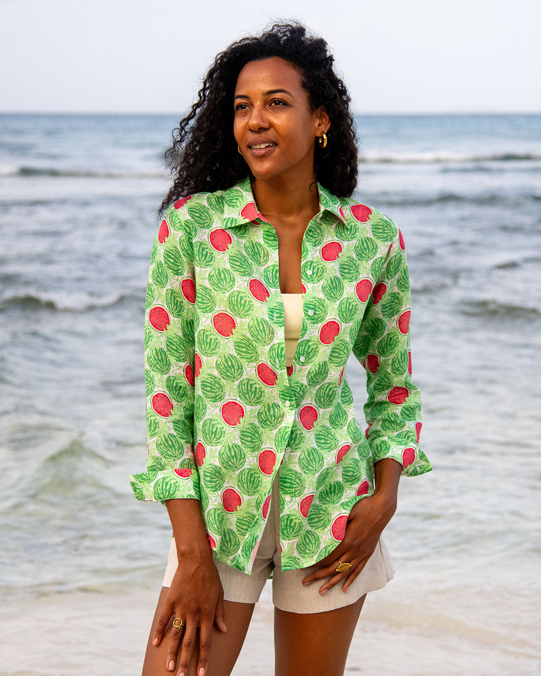 Woman wearing Anastasia oversized linen shirt in Watermelon Green print with natural linen shorts on the beach