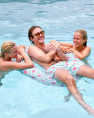 Man wearing Watermelon print swim shorts relaxing on an inflatable in a swimming pool