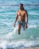 Tropical island style men’s Iguana Spruce swim shorts — sustainable, mid-length fit, perfect for beach and travel.