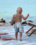Back view of little boy wearing Watermelon print boys' swim shorts at the beach