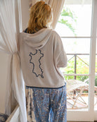 Woman wearing a 100% Mongolian cashmere hoodie by Pink House Mustique featuring the outline of Mustique on the back
