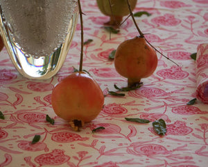 Pomegranates in a vase table decorations on floral print tablecloth by British fashion and interiors designer Lotty B Mustique
