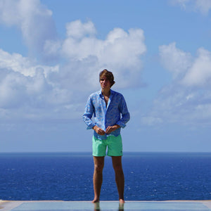 Mens premium swim shorts in solid green worn with whale blue linen shirt by designer Lotty B Mustique for Pink House holiday clothing